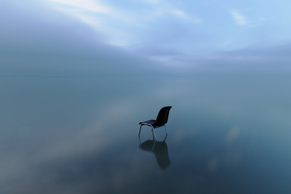 single chair reflecting water surface stormy day